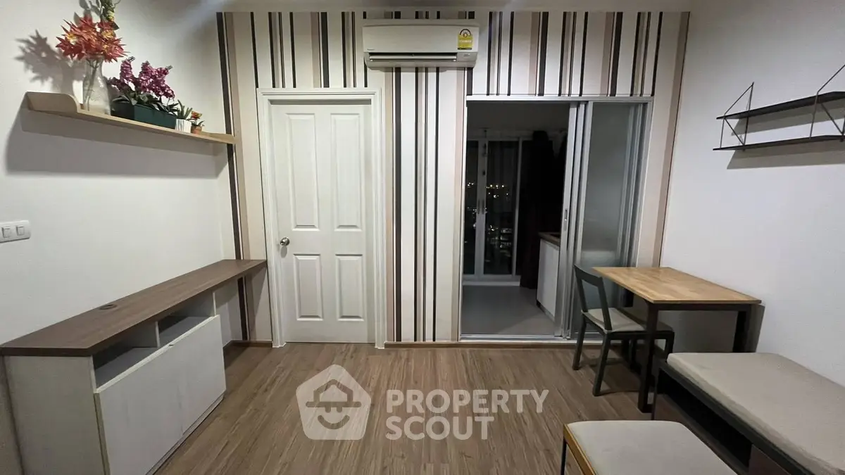 Modern living room with stylish decor and wooden flooring, featuring air conditioning and balcony access.