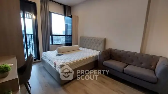 Modern bedroom with balcony view, featuring a stylish bed and cozy sofa in a well-lit space.