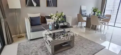 Modern living room with elegant decor and dining area, featuring stylish furniture and natural light.