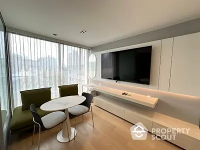 Modern living room with sleek furniture and large TV, featuring elegant design and natural light.