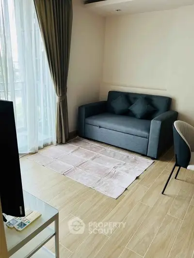 Modern living room with cozy sofa and large window, perfect for relaxation.