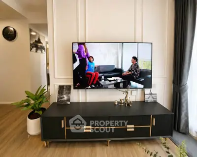 Modern living room with stylish TV console and wall-mounted flat screen, featuring elegant decor and wooden flooring.