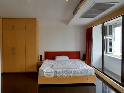 Spacious bedroom with large window and modern furnishings in urban apartment