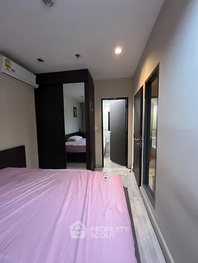 Cozy bedroom with pink bedding and modern wardrobe, featuring an ensuite bathroom.