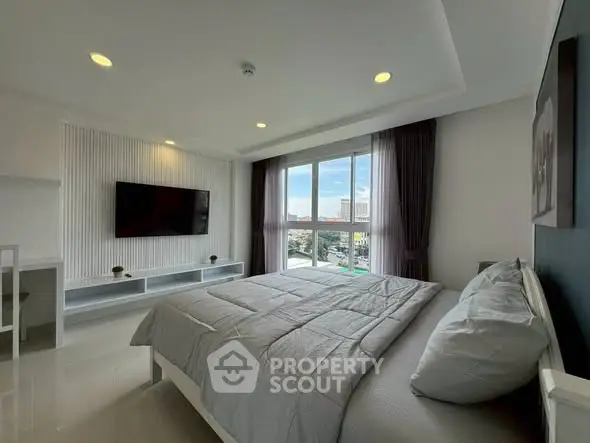 Modern bedroom with large window and wall-mounted TV, offering a bright and inviting atmosphere.