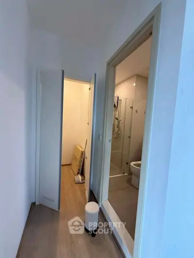 Compact hallway leading to a modern bathroom with glass shower enclosure.