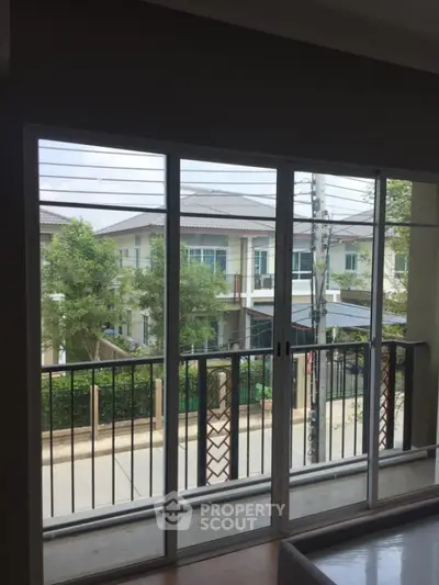 Spacious balcony with sliding glass doors offering a serene neighborhood view.