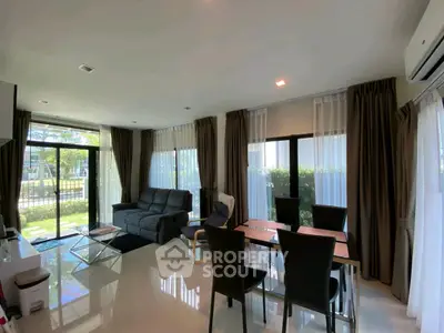 Modern living room with large windows and stylish furniture, offering a bright and inviting atmosphere.