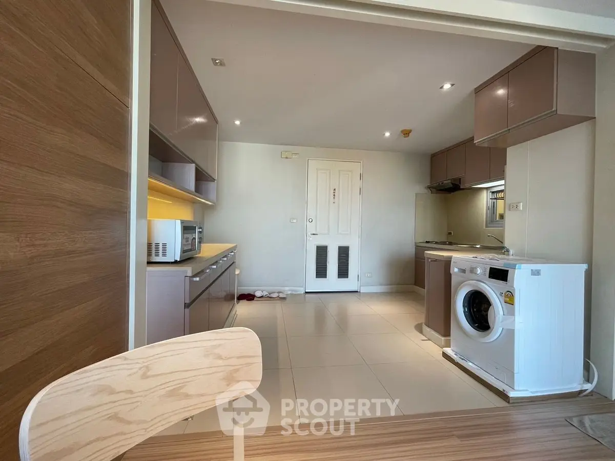 Modern kitchen with sleek cabinetry and built-in appliances, featuring a washing machine and microwave.