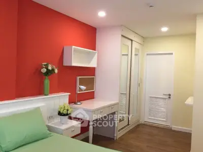 Charming bedroom with vibrant red accent wall and cozy decor, perfect for a stylish urban retreat.