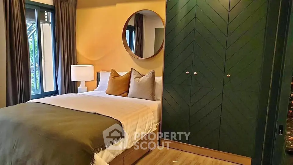 Cozy bedroom with stylish green wardrobe and round mirror, perfect for modern living.