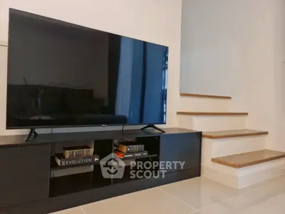 Modern living room with sleek TV setup and stylish staircase