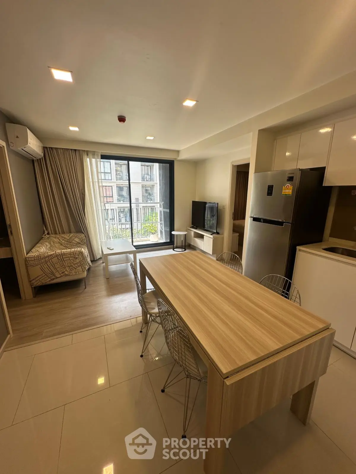 Modern studio apartment with open layout, featuring a cozy living area, dining table, and kitchen with appliances.