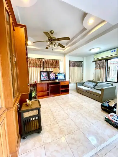 Spacious living room with ceiling fan and natural light, featuring elegant wooden furniture.