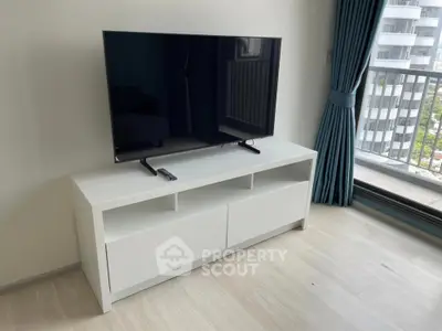 Modern living room with sleek TV stand and balcony view in urban apartment