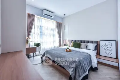 Modern bedroom with stylish decor and natural light, featuring a cozy bed and elegant furnishings.