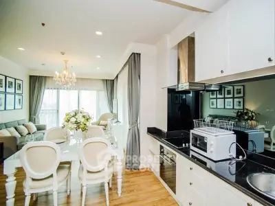 Elegant open-layout living and dining area with modern kitchen, chandelier, and large windows.