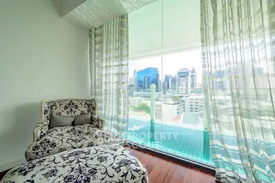 Luxurious living room with elegant armchair and stunning city view from large window.