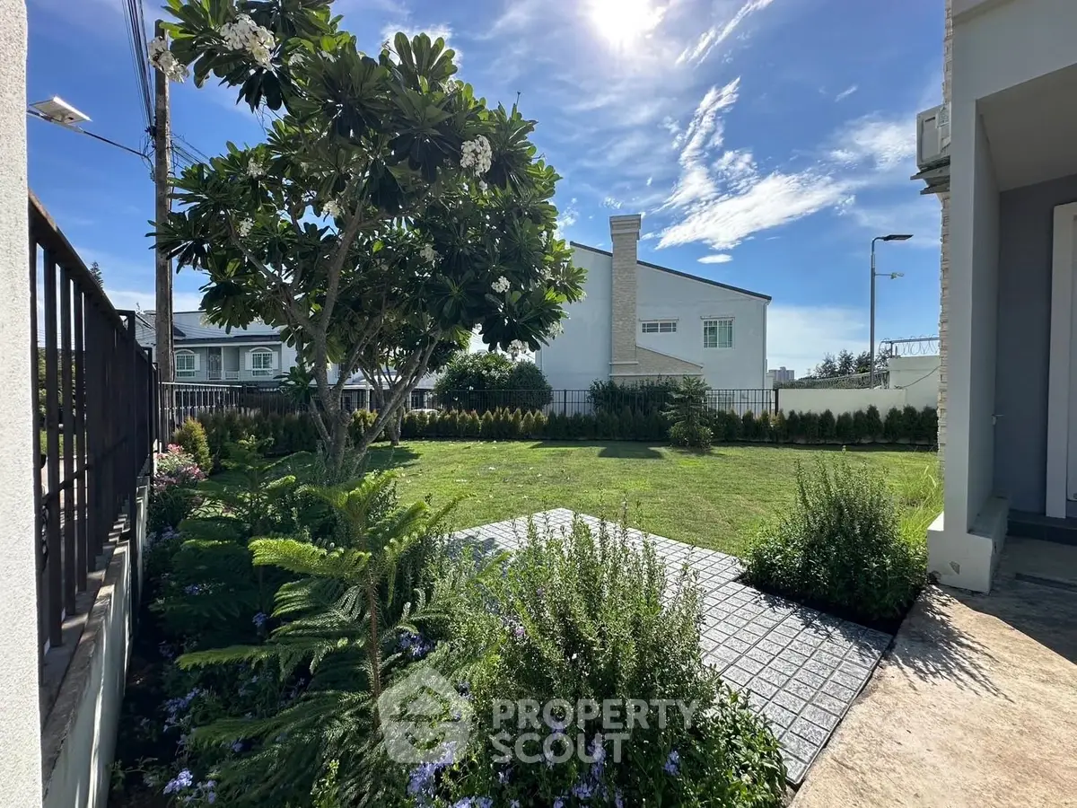 Charming garden view with lush greenery and modern architecture under a clear blue sky.