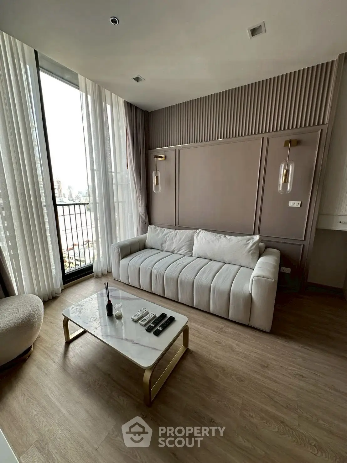 Modern living room with elegant decor and city view balcony, featuring a plush sofa and stylish coffee table.