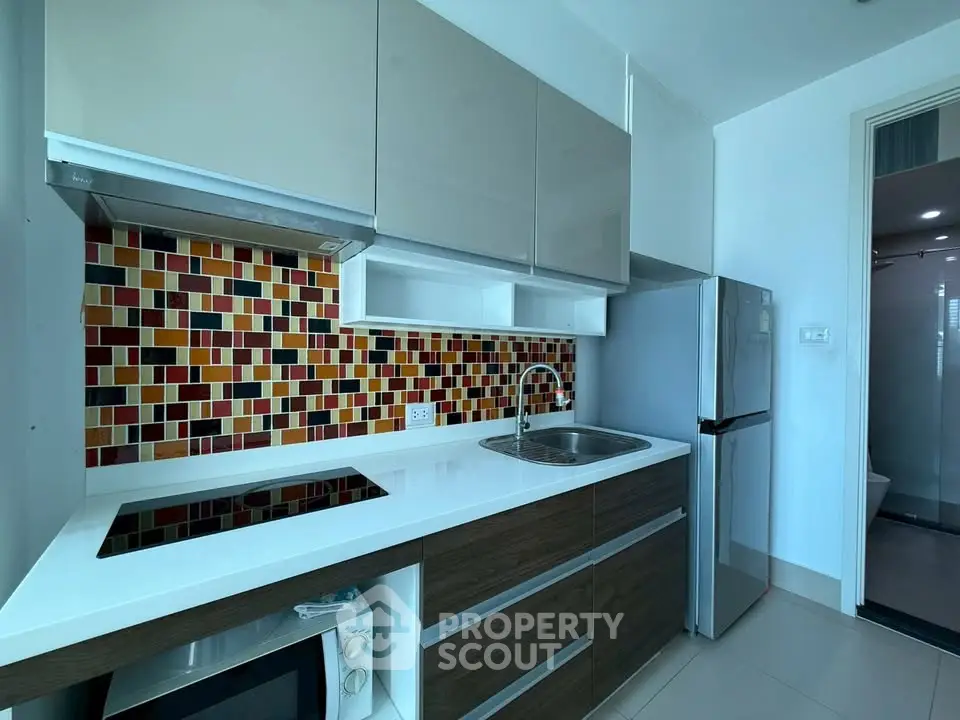 Modern kitchen with colorful backsplash and sleek appliances in a stylish apartment.