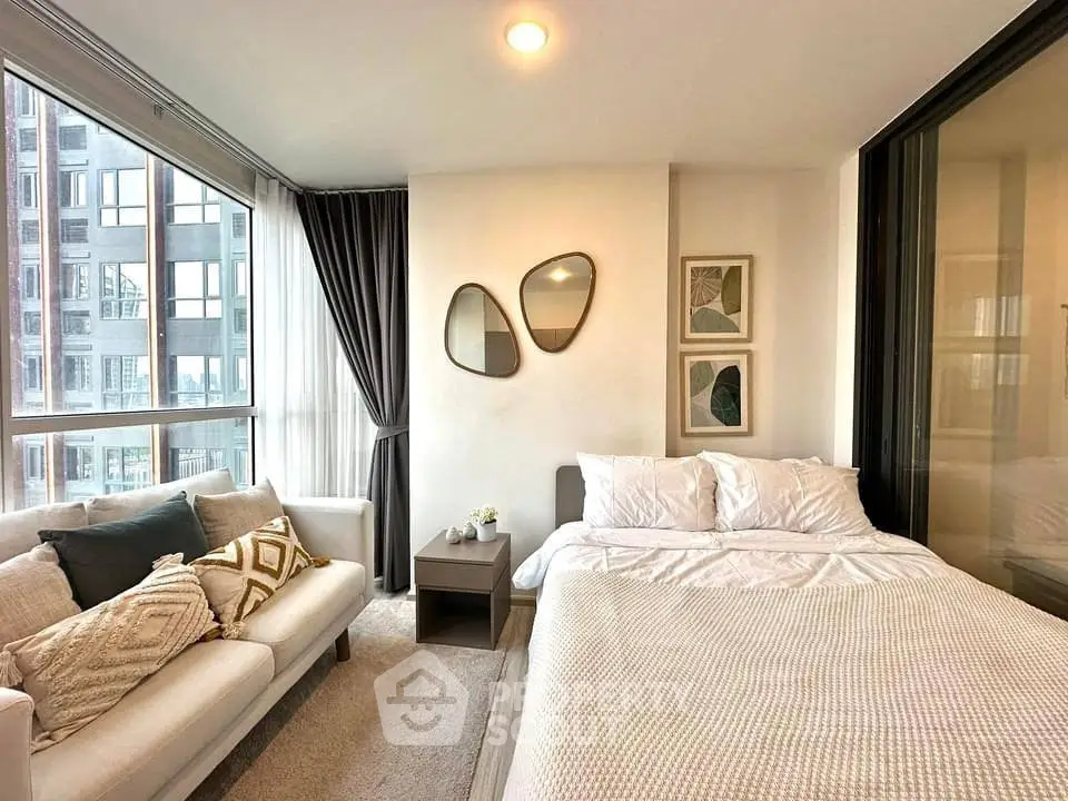 Modern bedroom with cozy seating and large windows in urban apartment