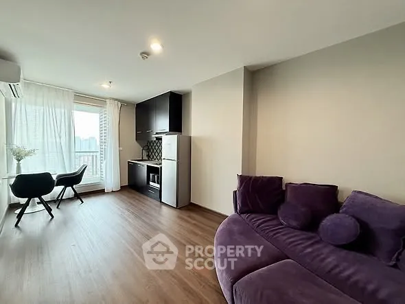Modern living room with stylish purple sofa and compact kitchen area