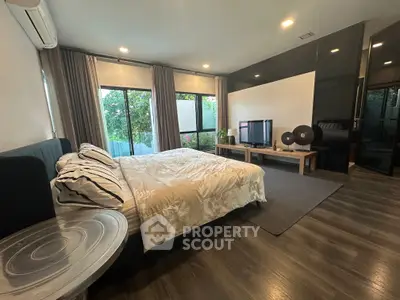 Spacious bedroom with modern decor and large windows offering garden views.