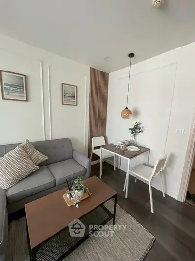 Modern living room with cozy sofa and dining area, stylish decor and pendant lighting.