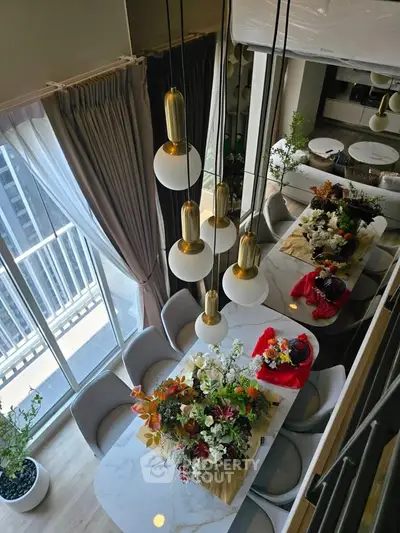 Elegant dining area with modern lighting and floral decor in a high-rise apartment.