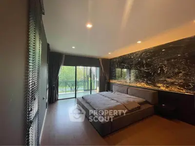 Luxurious bedroom with modern design and large window opening to a scenic balcony view.