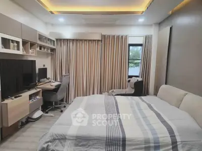 Modern bedroom with cozy decor and workspace, featuring a large bed and stylish furnishings.