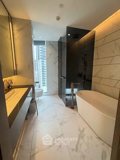 Luxurious modern bathroom with marble tiles and freestanding bathtub in high-rise apartment.
