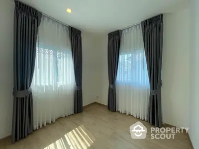 Bright and airy unfurnished room with large windows draped in elegant curtains, ready for personalization in a modern home.