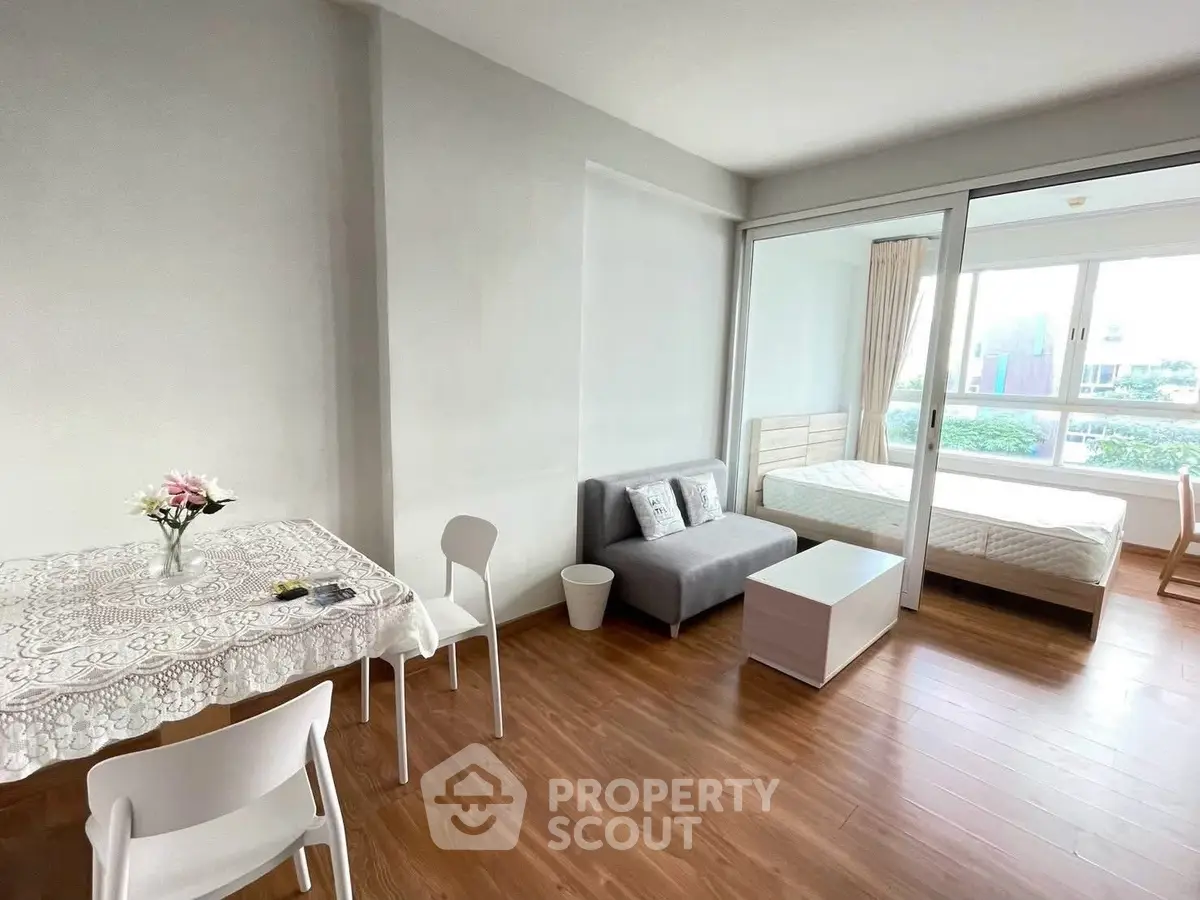 Modern studio apartment with open layout, featuring a cozy living area and bedroom with large windows.