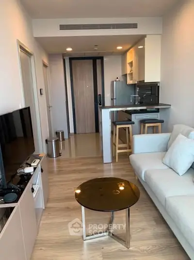 Modern living room with open kitchen, sleek furniture, and stylish decor in a cozy apartment.