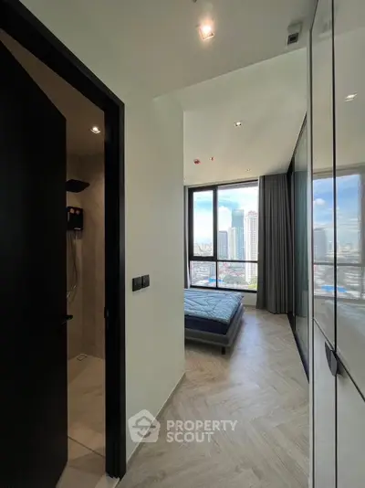 Modern bedroom with city view and adjacent bathroom in high-rise apartment.