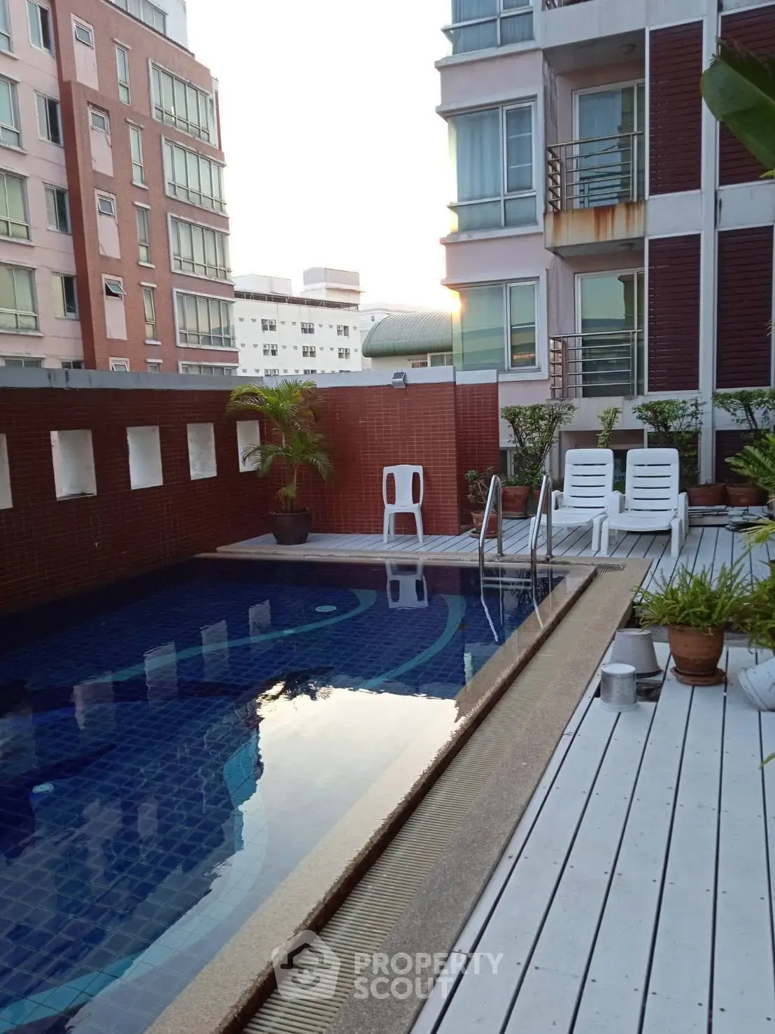 Luxurious apartment building with rooftop pool and sun loungers, perfect for relaxation and city views.