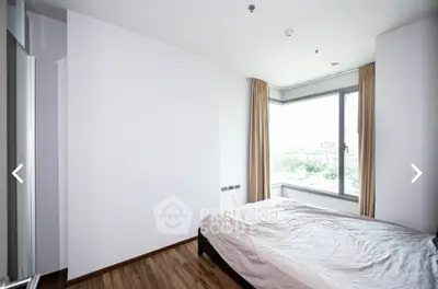 Bright bedroom with large window and wooden flooring offering city views.
