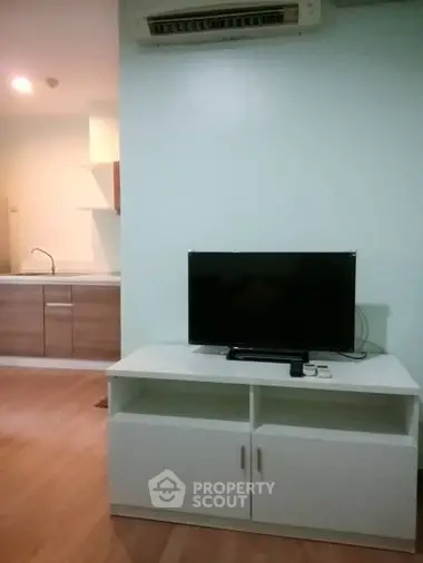 Modern living room with TV and open kitchen layout in a cozy apartment.