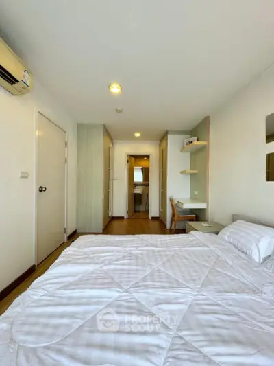 Spacious bedroom with modern decor and natural light, featuring a cozy bed and built-in storage.