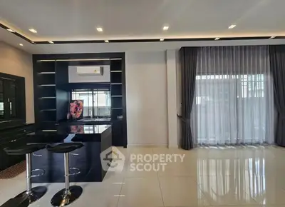 Modern kitchen with sleek black countertops and bar stools in a spacious open layout.