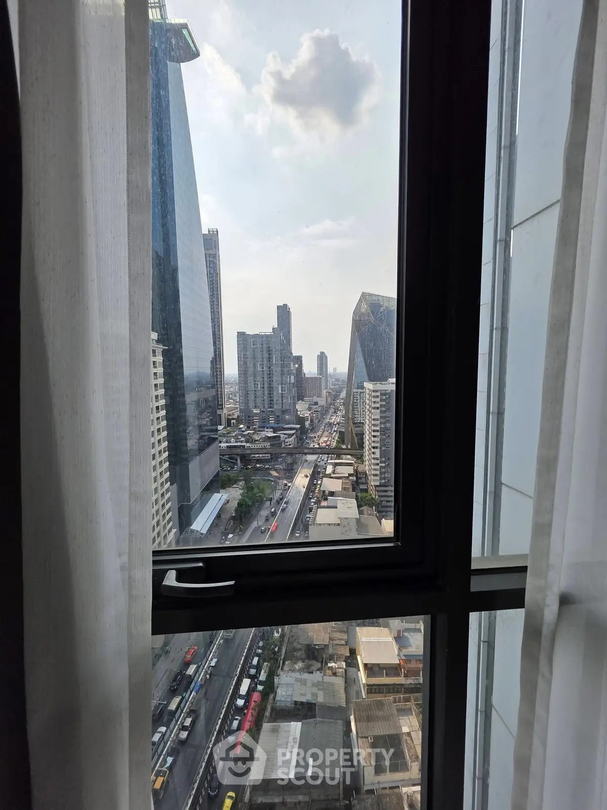 Stunning cityscape view from high-rise apartment window, showcasing urban skyline and bustling streets below.