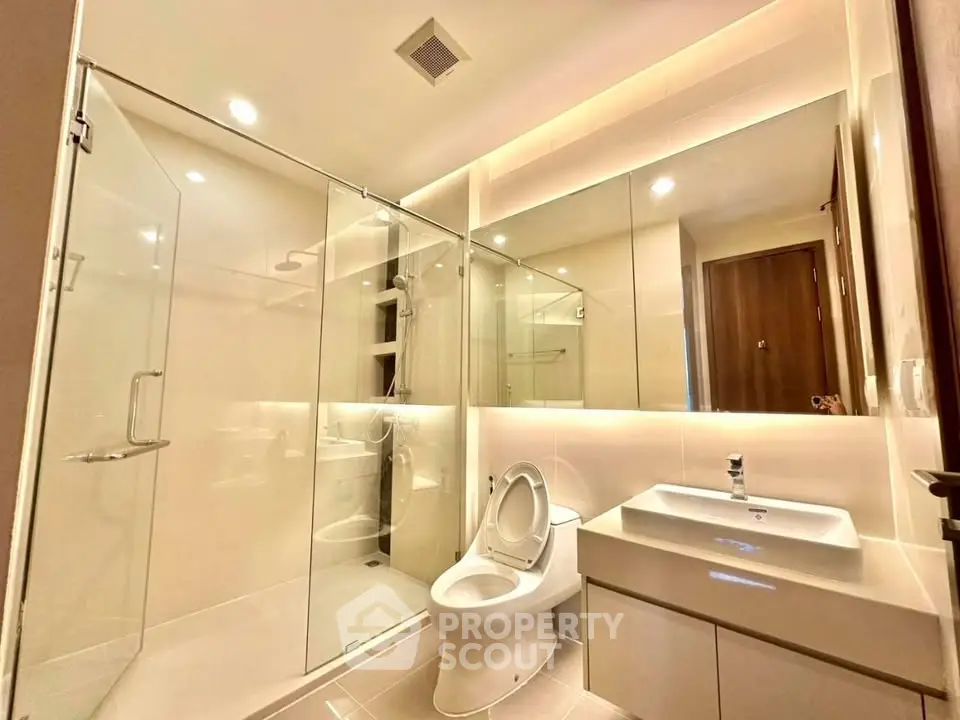 Modern bathroom with glass shower and sleek fixtures in luxury apartment.