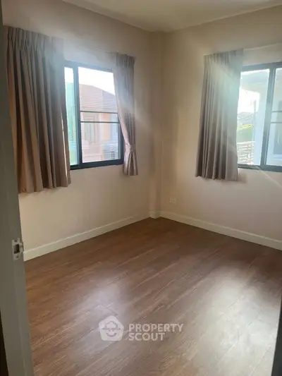 Bright empty room with wooden flooring and large windows