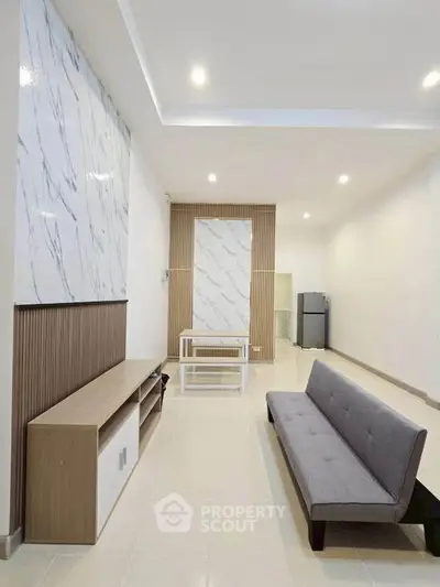 Modern living room with sleek furniture and marble accents, featuring a minimalist design and ambient lighting.