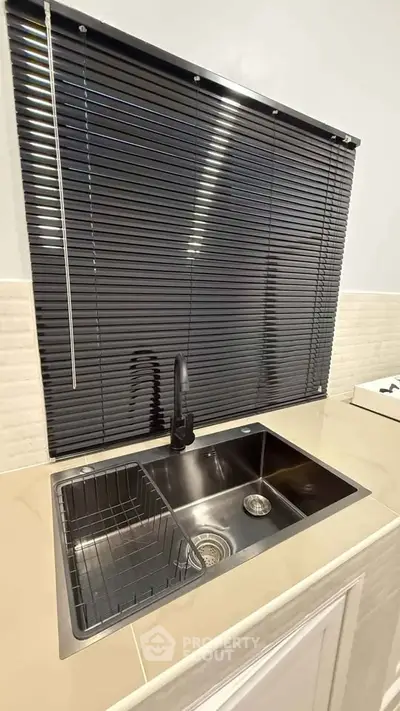 Modern kitchen sink with sleek black blinds and stylish faucet in contemporary home.