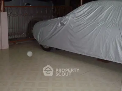 Spacious garage with tiled flooring and covered vehicle