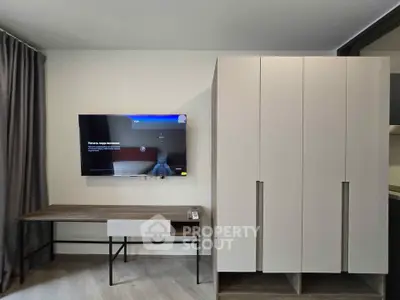 Modern study area with sleek desk, wall-mounted TV, and stylish wardrobe in contemporary apartment.