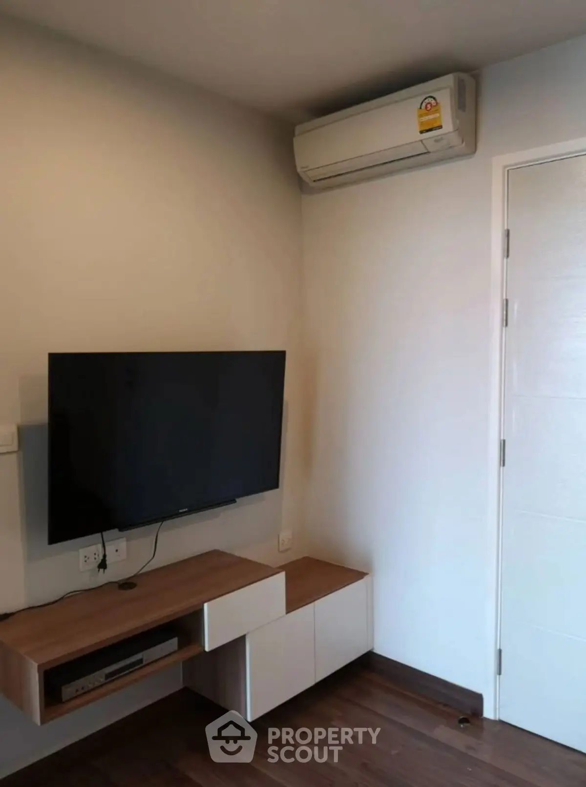 Modern living room corner with wall-mounted TV and air conditioning unit.